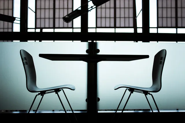 A dark room with two empty chairs facing each other across a table