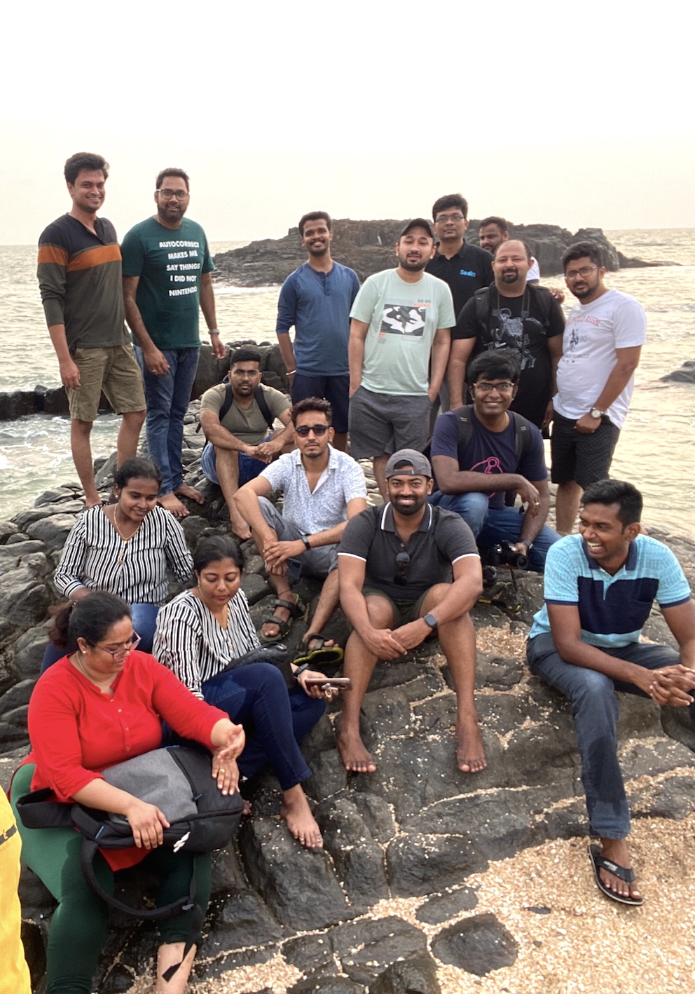 A group of smiling Tarkans, some sitting and some standing, on the smooth rocks of a coastline
