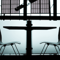 A dark room with two empty chairs facing each other across a table