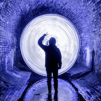 Silhouette of a man standing inside a glowing blue tunnel with a glowing white circle in front of him